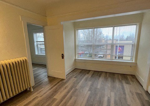 an empty living room with a radiator and a window